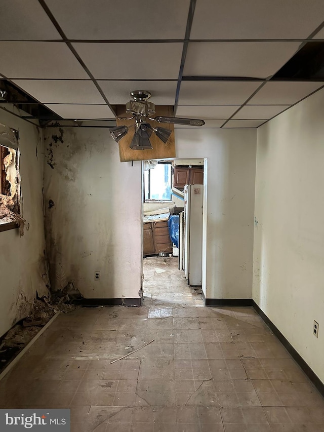 unfurnished room with a ceiling fan, a drop ceiling, and baseboards