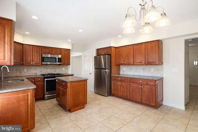 kitchen featuring stone countertops, decorative backsplash, appliances with stainless steel finishes, brown cabinets, and a sink