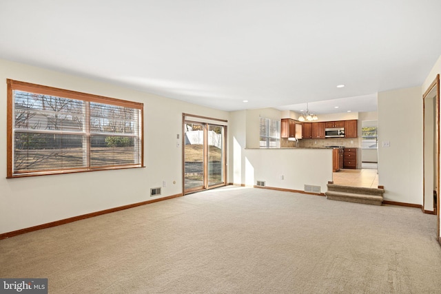 unfurnished living room featuring light carpet, visible vents, and baseboards