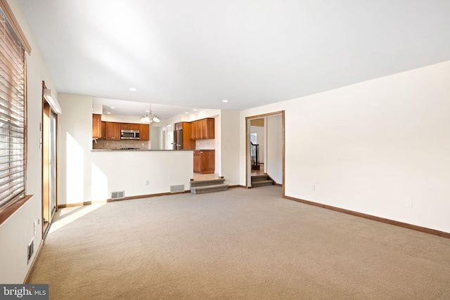 unfurnished living room with light carpet, visible vents, baseboards, and an inviting chandelier