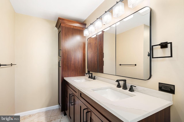 bathroom with marble finish floor, a sink, baseboards, and double vanity