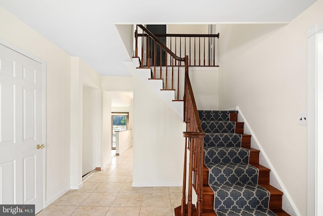 staircase featuring baseboards and tile patterned floors