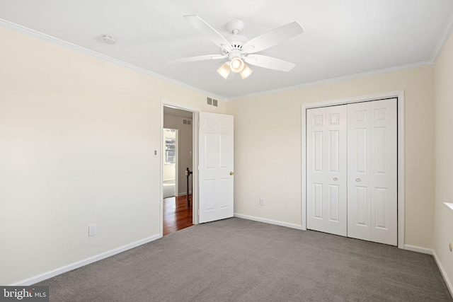 unfurnished bedroom with carpet, crown molding, a closet, visible vents, and baseboards