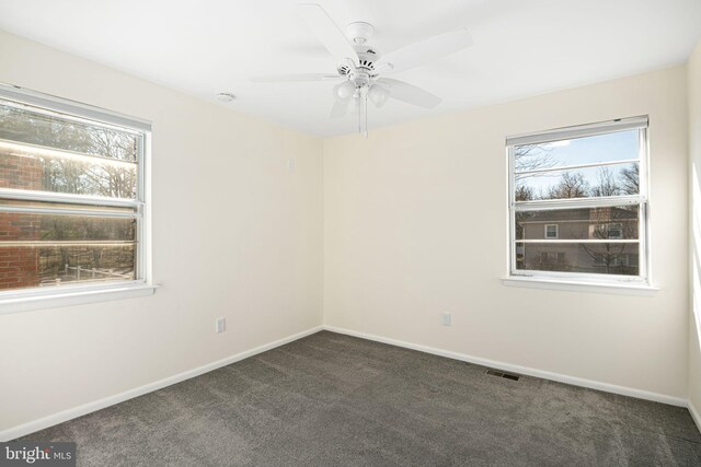 carpeted spare room featuring ceiling fan, a wealth of natural light, visible vents, and baseboards