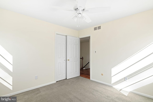 unfurnished bedroom with carpet floors, a closet, visible vents, ceiling fan, and baseboards