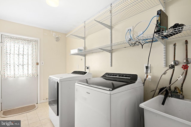 laundry area with laundry area, independent washer and dryer, a sink, and light tile patterned floors