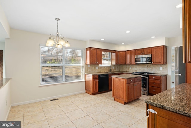 kitchen featuring tasteful backsplash, baseboards, visible vents, dark stone countertops, and stainless steel appliances