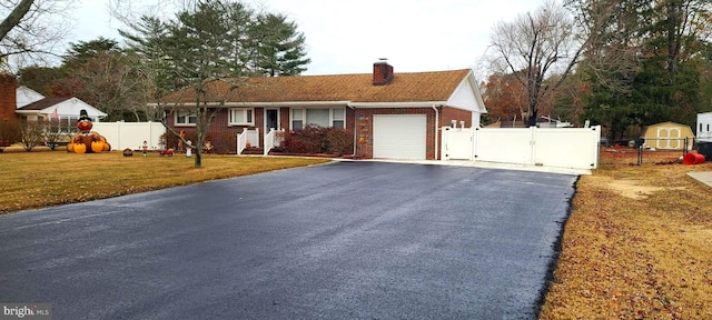 single story home with a chimney, aphalt driveway, a gate, fence, and brick siding