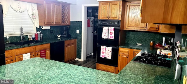 kitchen with black appliances, backsplash, a sink, and brown cabinetry