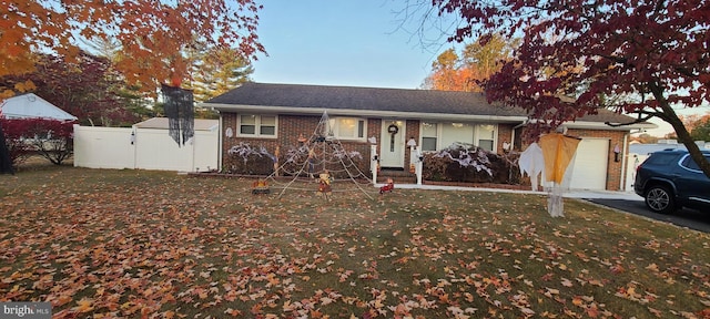 ranch-style home with brick siding, fence, driveway, a gate, and a front yard