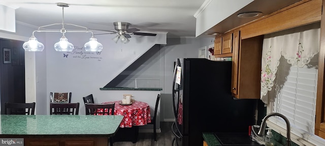 kitchen featuring ceiling fan, ornamental molding, brown cabinets, pendant lighting, and a sink