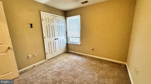 unfurnished bedroom with visible vents, carpet floors, baseboards, and a closet