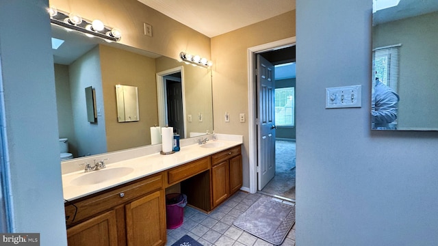 full bathroom featuring a sink, toilet, double vanity, and tile patterned flooring