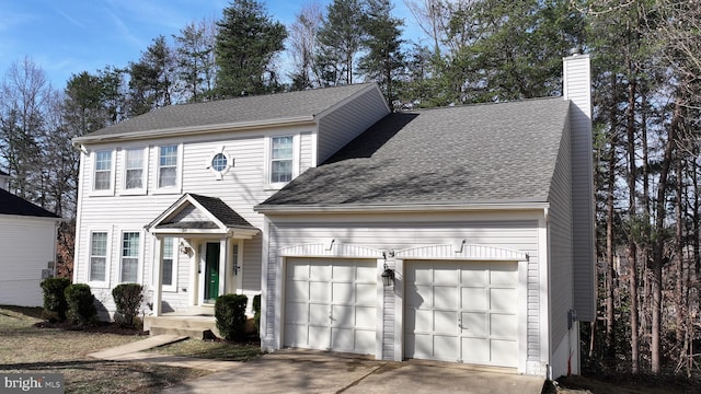 colonial-style house with a chimney, concrete driveway, an attached garage, and a shingled roof