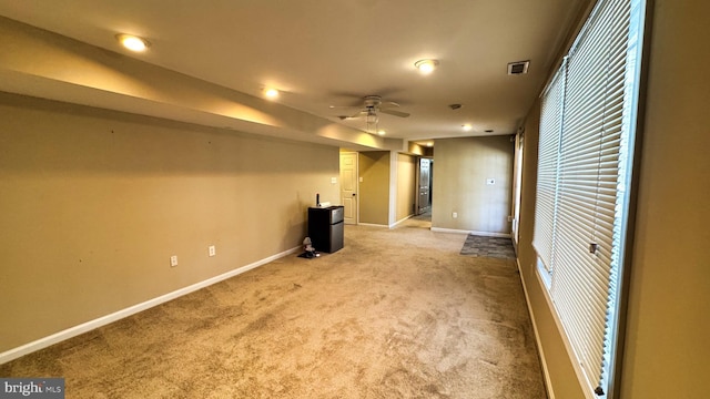 spare room featuring visible vents, baseboards, a ceiling fan, and carpet flooring