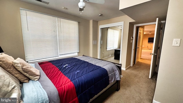 carpeted bedroom with a closet, baseboards, visible vents, and ceiling fan