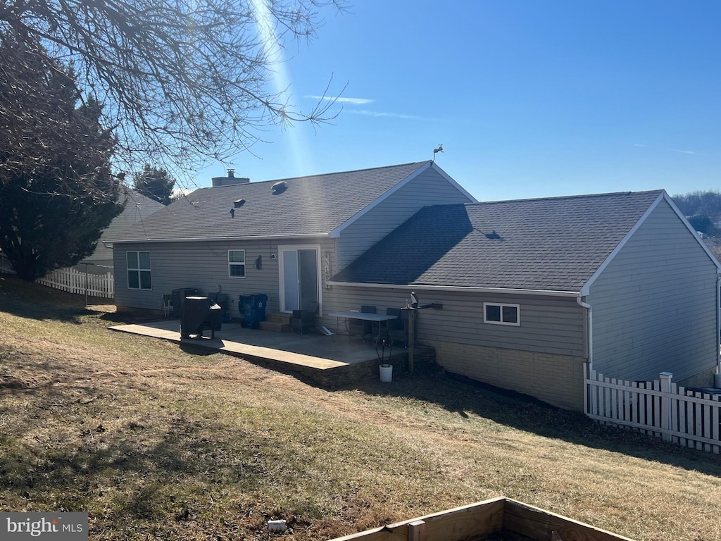 back of house featuring brick siding, a patio, fence, and a lawn