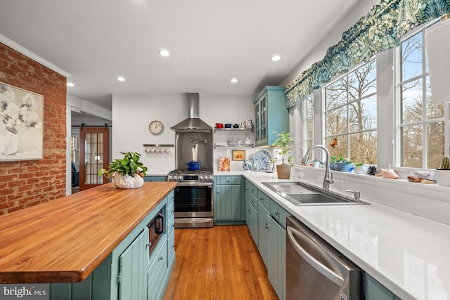 kitchen featuring green cabinets, wall chimney exhaust hood, appliances with stainless steel finishes, and a barn door