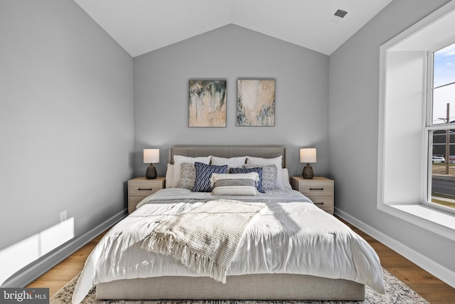 bedroom with visible vents, baseboards, vaulted ceiling, and wood finished floors