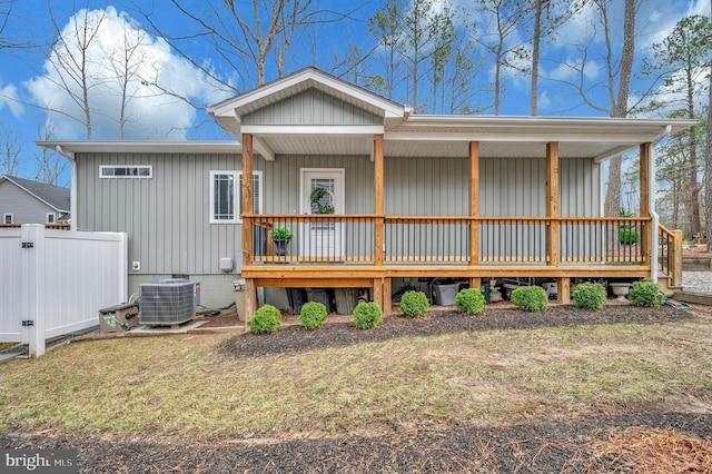 rear view of house with board and batten siding, covered porch, fence, and central air condition unit