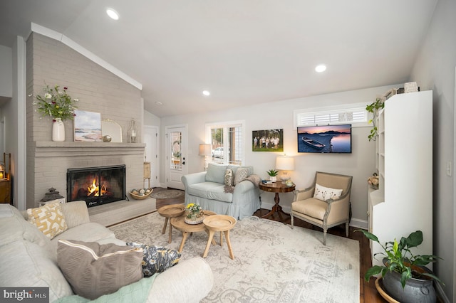 living room with recessed lighting, a brick fireplace, vaulted ceiling, and wood finished floors