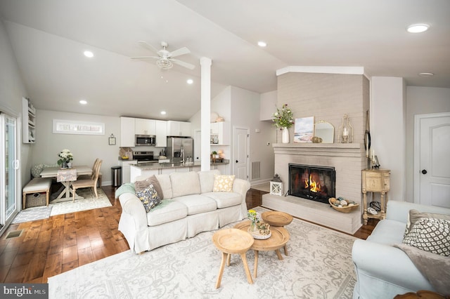 living room with lofted ceiling, recessed lighting, a fireplace, wood finished floors, and visible vents