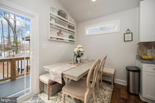 dining space featuring lofted ceiling, dark wood-style flooring, and baseboards