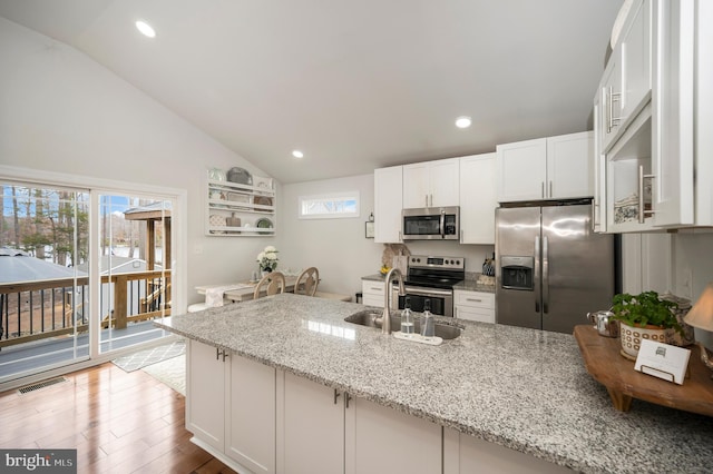 kitchen featuring lofted ceiling, visible vents, appliances with stainless steel finishes, white cabinets, and wood finished floors