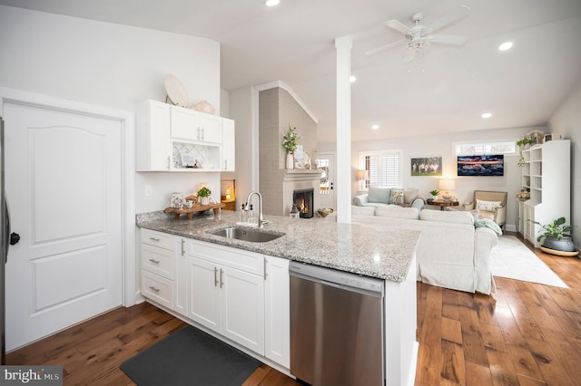 kitchen with lofted ceiling, white cabinets, a sink, dishwasher, and a peninsula