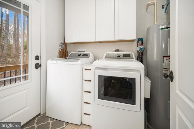 clothes washing area featuring cabinet space, water heater, and independent washer and dryer