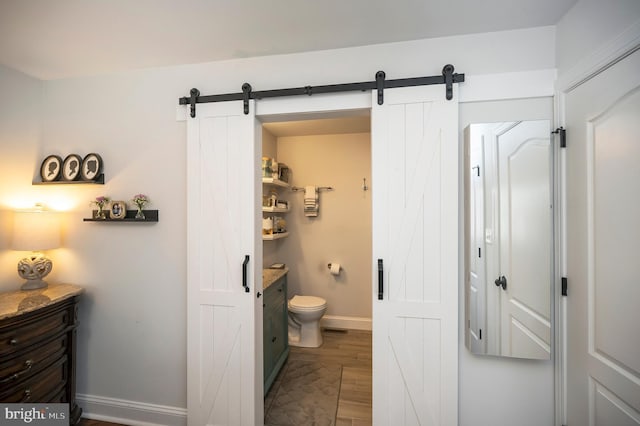 bathroom featuring wood finished floors, vanity, toilet, and baseboards