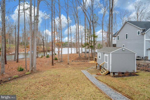 view of yard featuring a water view, an outdoor structure, and a shed