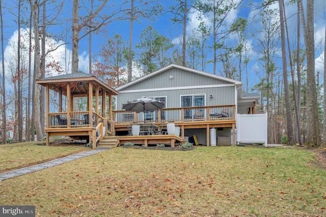 rear view of property featuring a lawn, a wooden deck, and a gazebo