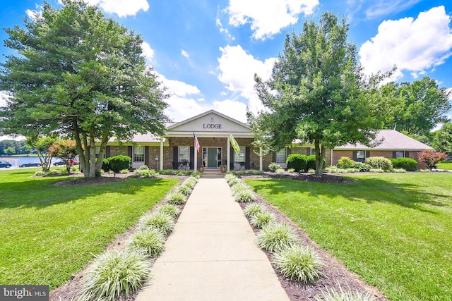 view of front of home with covered porch, brick siding, and a front yard