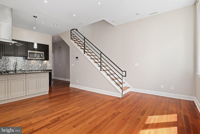 kitchen with light wood-style flooring, stainless steel microwave, decorative backsplash, and baseboards