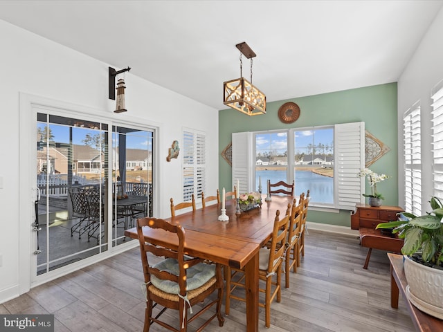 dining room with a wealth of natural light, baseboards, an inviting chandelier, and light wood-style flooring