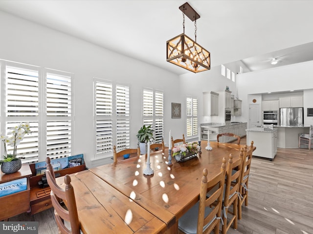 dining space featuring light wood-style flooring and ceiling fan with notable chandelier