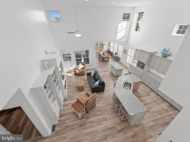 living area featuring recessed lighting, a high ceiling, light wood-style flooring, and a ceiling fan