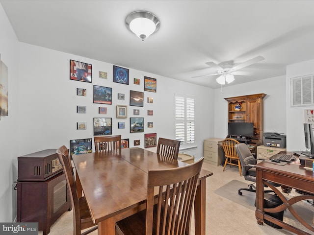 dining space featuring light colored carpet and ceiling fan