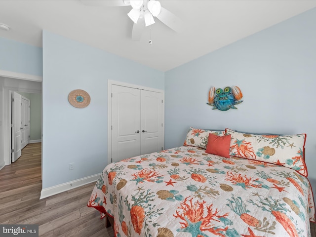 bedroom with a closet, a ceiling fan, baseboards, and wood finished floors