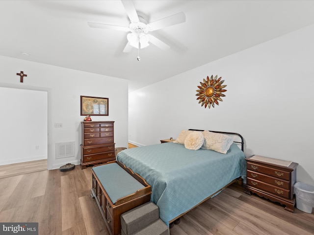 bedroom featuring ceiling fan, visible vents, baseboards, and wood finished floors