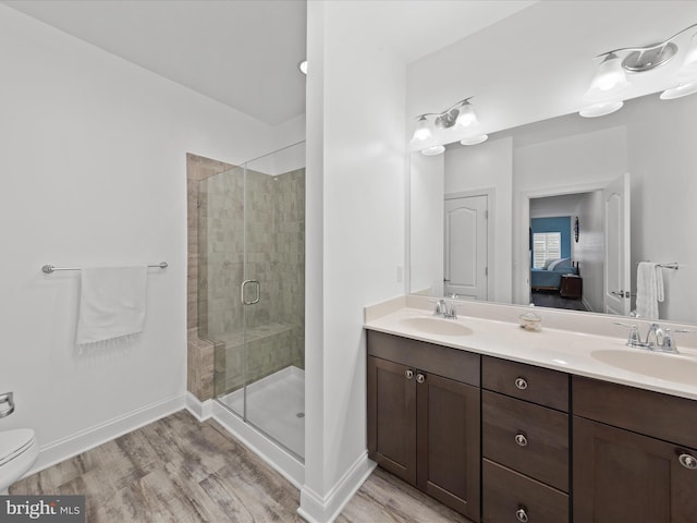 bathroom with double vanity, a stall shower, wood finished floors, and a sink