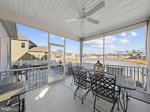 sunroom / solarium featuring a ceiling fan, a residential view, and a water view