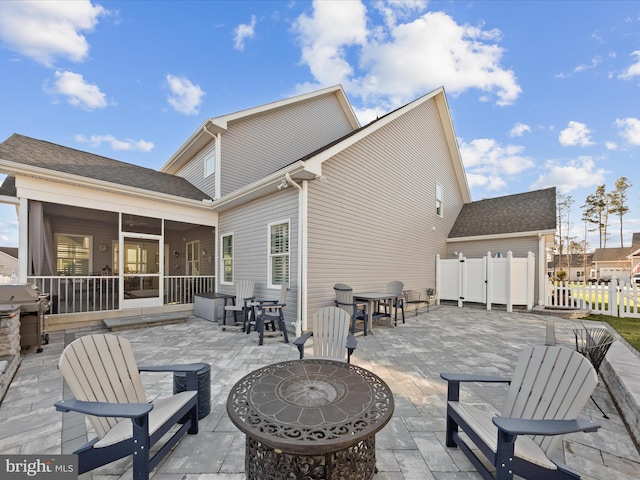 back of property with fence, a patio, and a sunroom