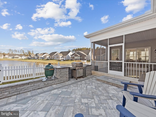 view of patio / terrace featuring a residential view, fence, a water view, and a sunroom