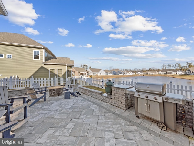 view of patio / terrace with area for grilling, an outdoor fire pit, fence, a residential view, and exterior kitchen