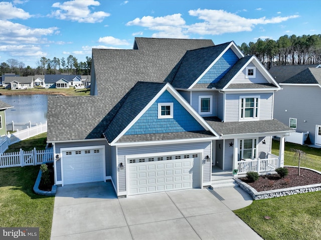 view of front of property featuring fence, an attached garage, covered porch, concrete driveway, and a water view