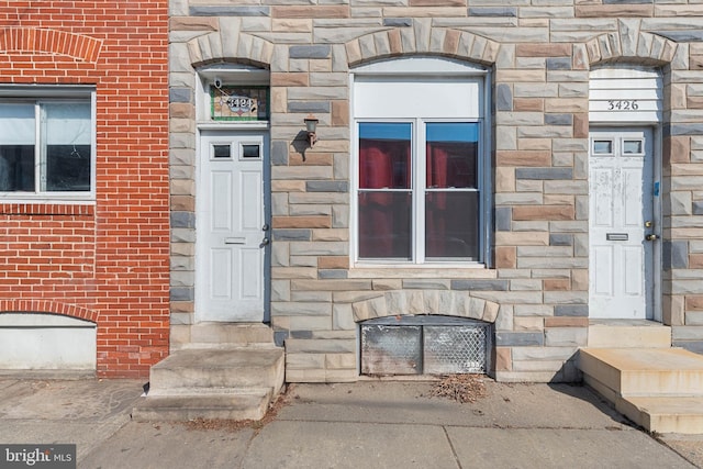 doorway to property featuring stone siding and brick siding