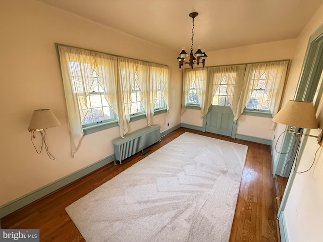 dining area with baseboards, a notable chandelier, radiator heating unit, and wood finished floors