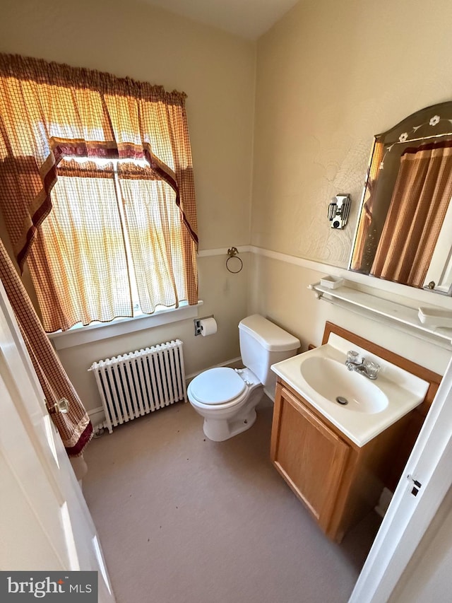 bathroom with toilet, vanity, and radiator heating unit